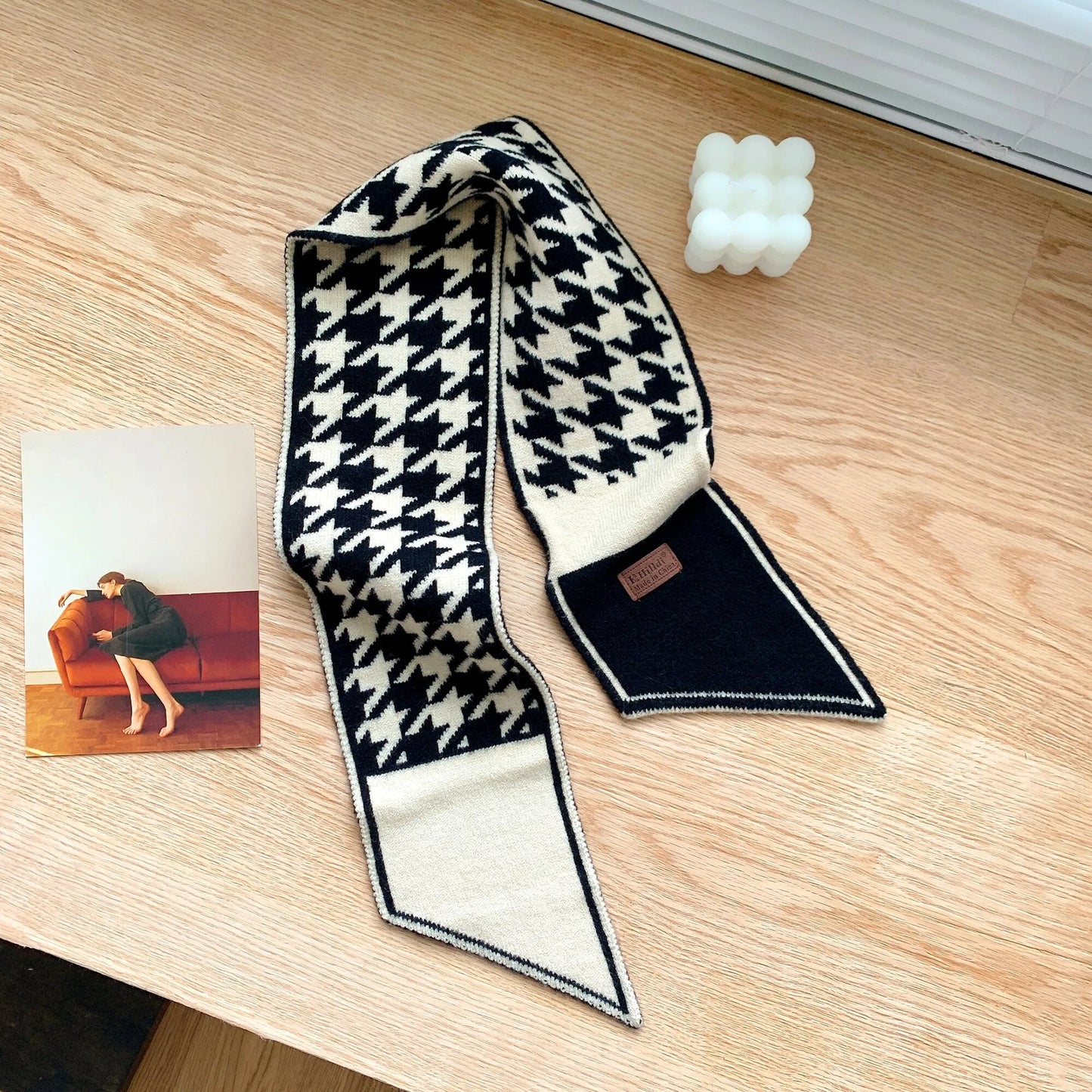 Schwarz-weißer Hahnentritt-Schal aus Wolle auf Holztisch, modisches Accessoire.
