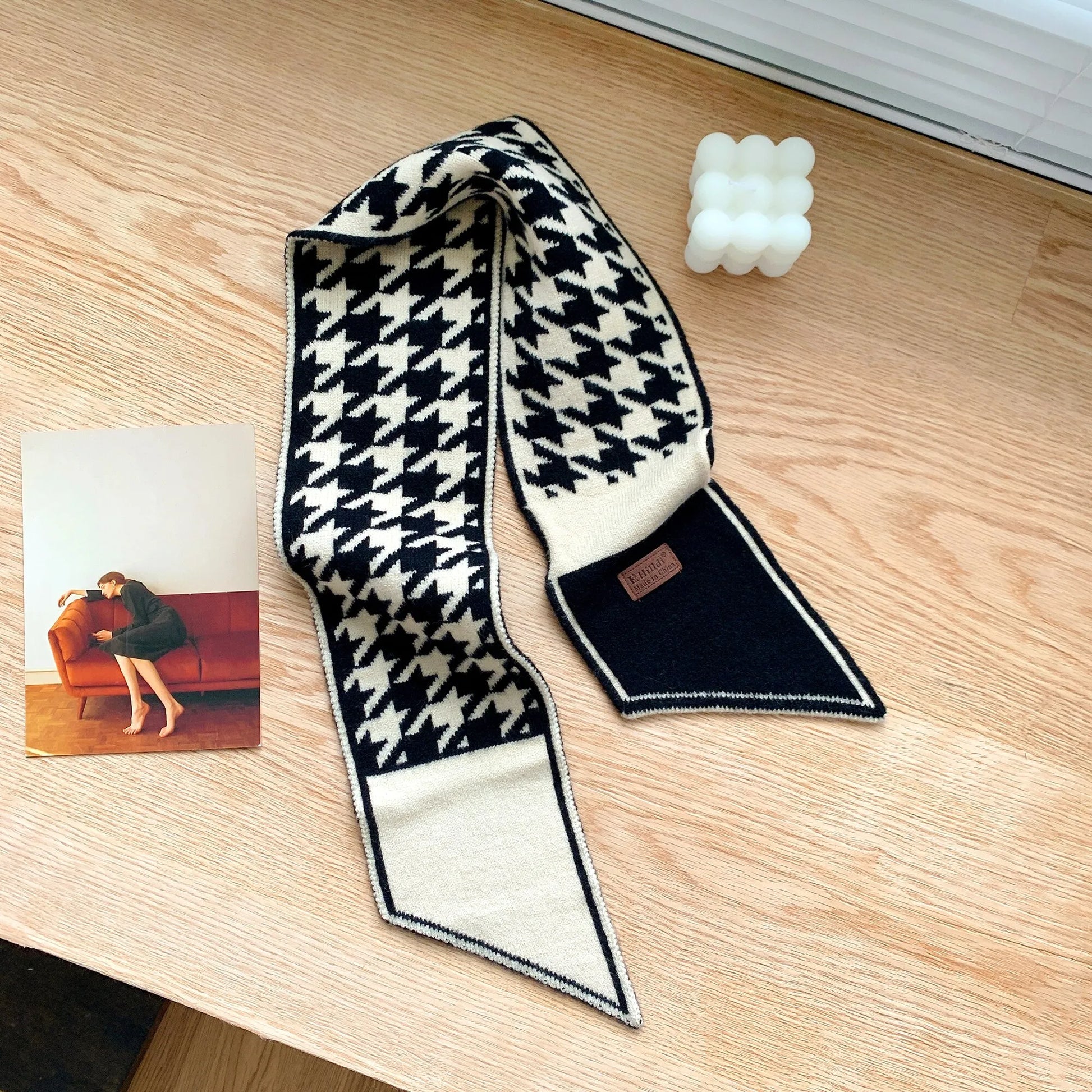 Schwarz-weißer Hahnentritt-Schal aus Wolle auf Holztisch, modisches Accessoire.