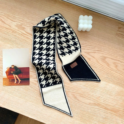 Schwarz-weißer Hahnentritt-Schal aus Wolle auf Holztisch, modisches Accessoire.