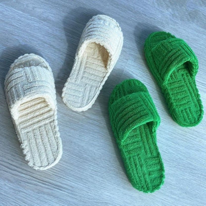 Grüne und weiße Badeschlappen aus Frottee auf Holzboden, bequem und rutschfest.