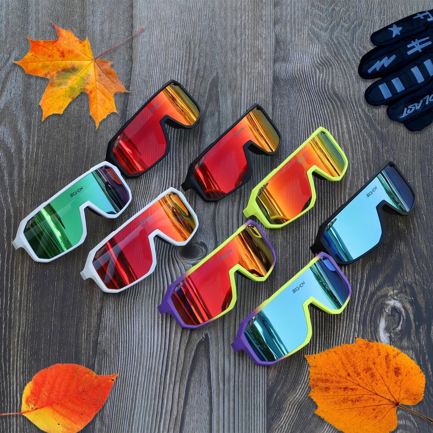 Bunte Sportsonnenbrillen auf Holztisch mit Herbstblättern, modische Accessoires für Outdoor-Aktivitäten.