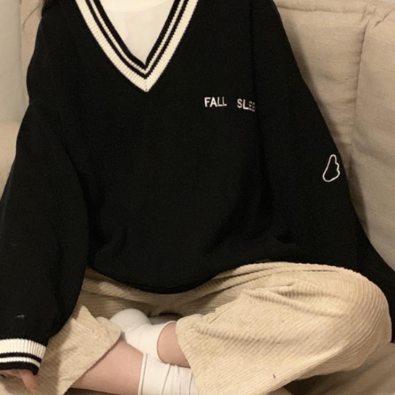 Schwarzer V-Ausschnitt Pullover mit Schriftzug, beige Cordhose, lässiger Herbst-Look.