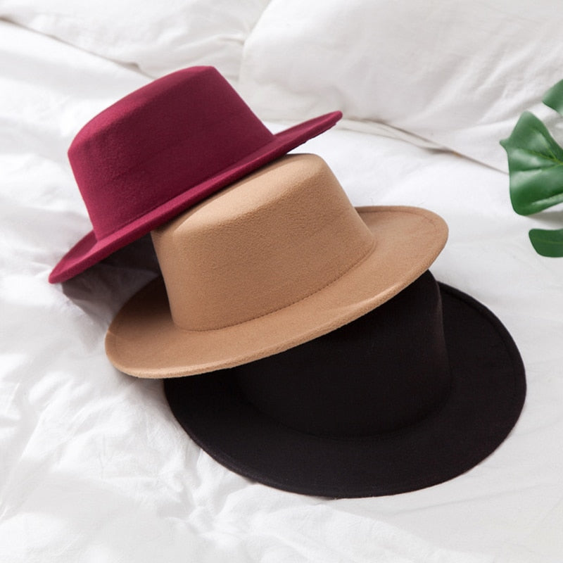 Zwei Filzhüte, rot und beige, auf weißem Bett, stilvolle Kopfbedeckung, Modeaccessoire.