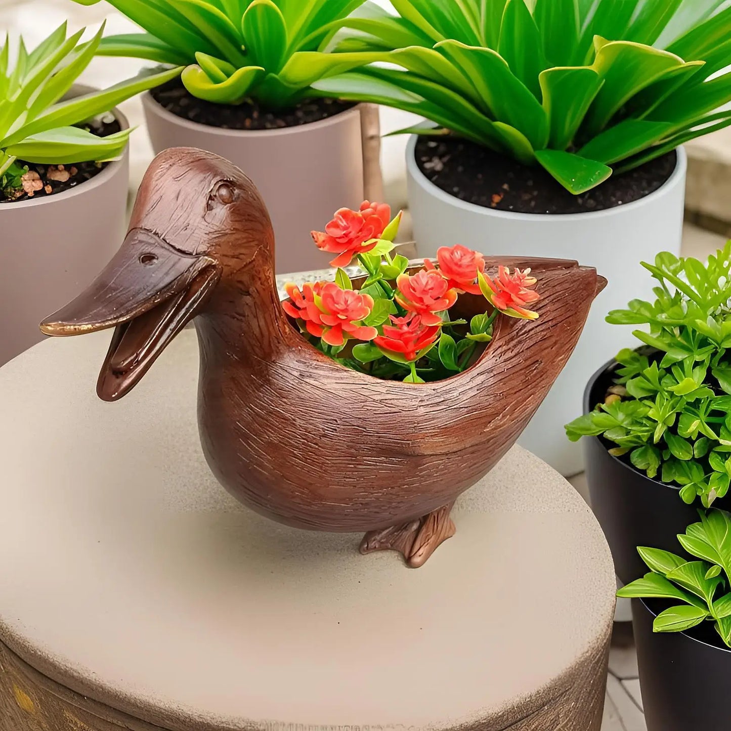 Entenförmiger Blumentopf aus Holz mit roten Blumen, umgeben von grünen Pflanzen in Töpfen.