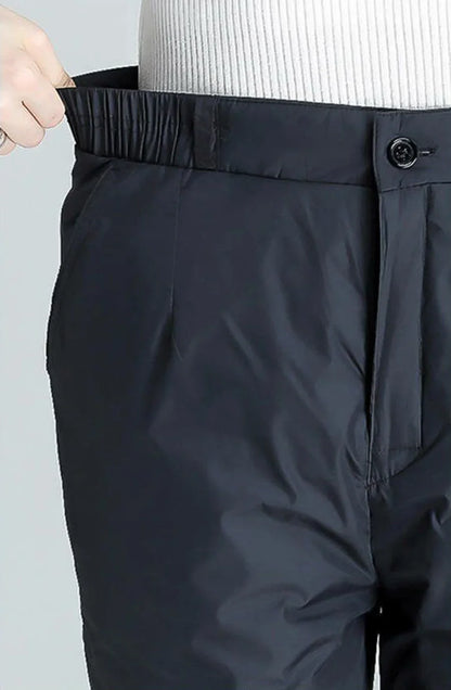 Schwarze, wasserdichte Hose mit elastischem Bund und Knopfverschluss für Outdoor-Aktivitäten.