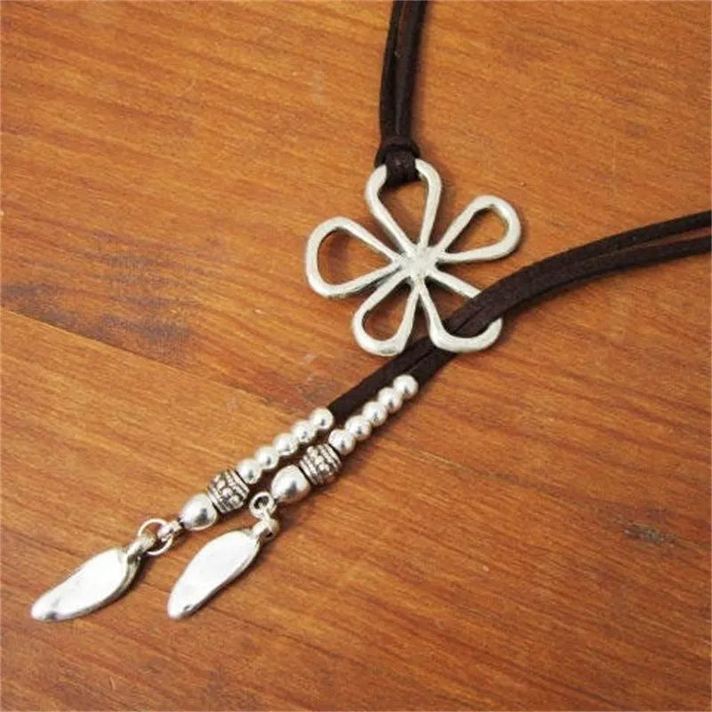 Silberne Blume Anhänger Halskette mit Lederband auf Holzoberfläche, Boho Schmuck Design.