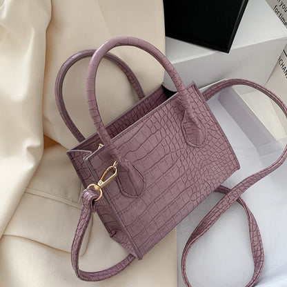 Lila Handtasche aus Krokodillederimitat mit Schulterriemen, elegant und modisch.