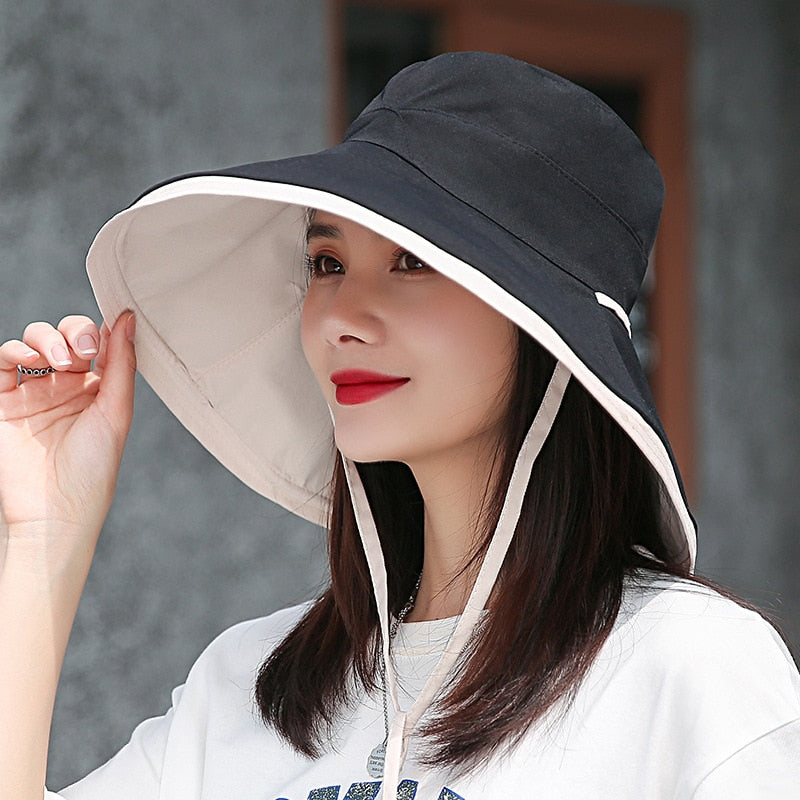 Frau mit schwarzem Sonnenhut, breiter Krempe, UV-Schutz, Sommermode, Outdoor-Accessoire.