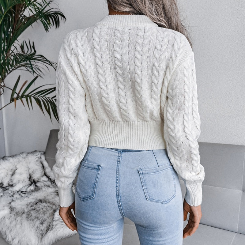 Frau in weißem Zopfmuster-Pullover und blauer Jeans, Rückansicht, modisch, gemütlich.