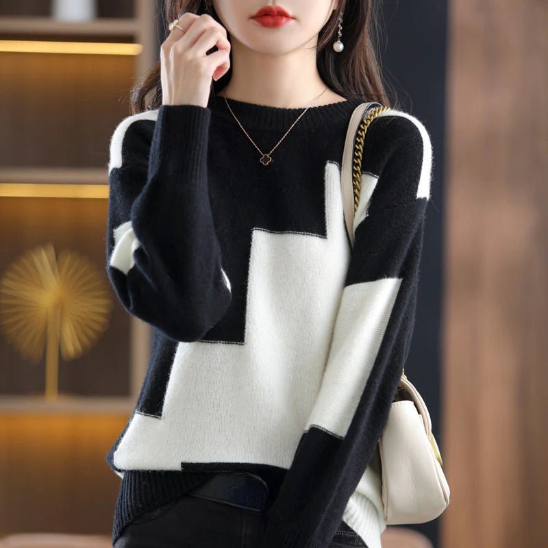Frau in schwarz-weißem geometrischem Pullover, goldene Kette, weiße Handtasche.