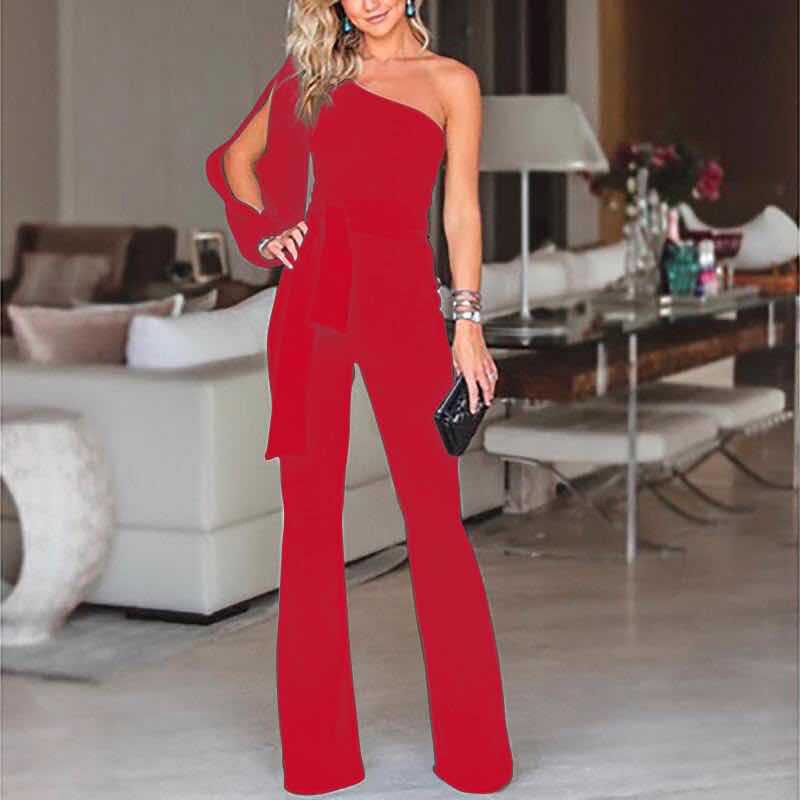 Frau in rotem, schulterfreiem Jumpsuit, elegantes Abendoutfit, moderne Wohnzimmerkulisse.