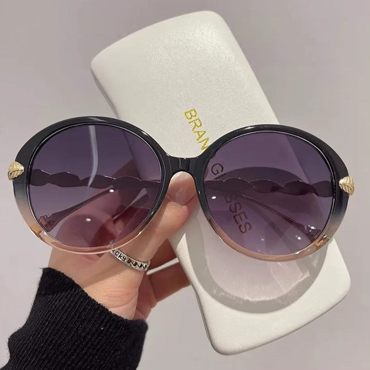 Schwarze runde Sonnenbrille mit lila Gläsern, Etui, Damenmode-Accessoire.