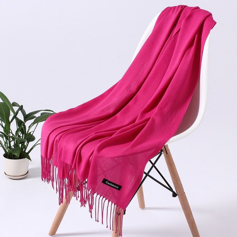 Pinkfarbener Kaschmirschal auf weißem Stuhl, weiche Textur, modisches Accessoire.