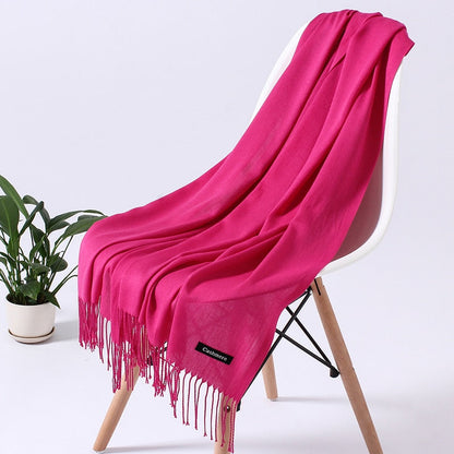 Pinkfarbener Kaschmirschal auf weißem Stuhl, weiche Textur, modisches Accessoire.