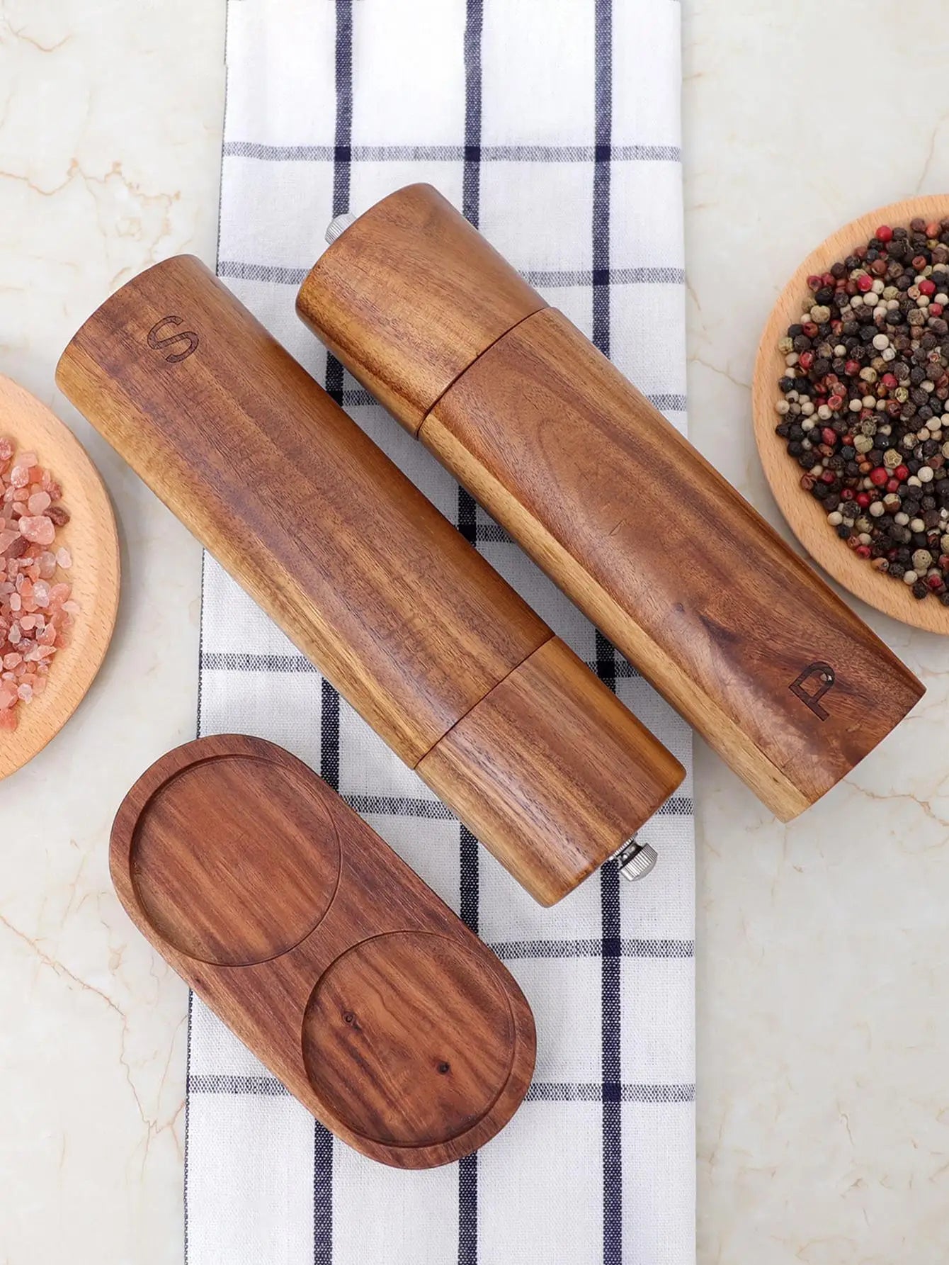Salz- und Pfeffermühlen aus Holz, graviert, auf kariertem Tuch, mit rosa und buntem Pfeffer.