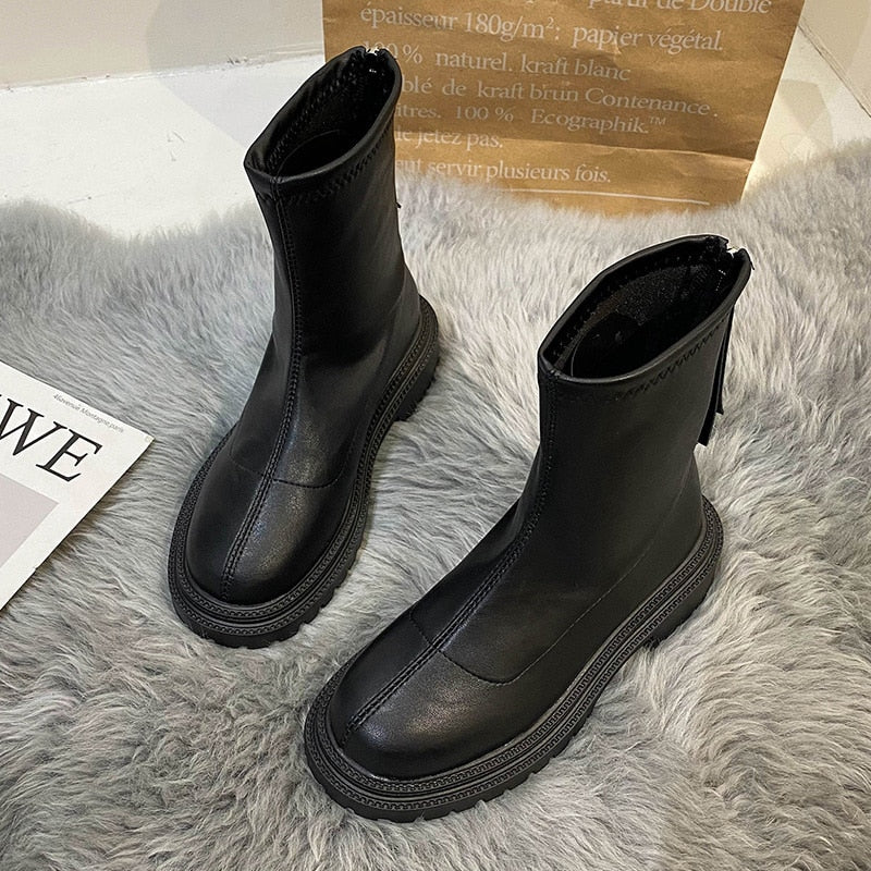 Schwarze Damenstiefel aus Leder mit Reißverschluss, modisch, robust, auf grauem Teppich.