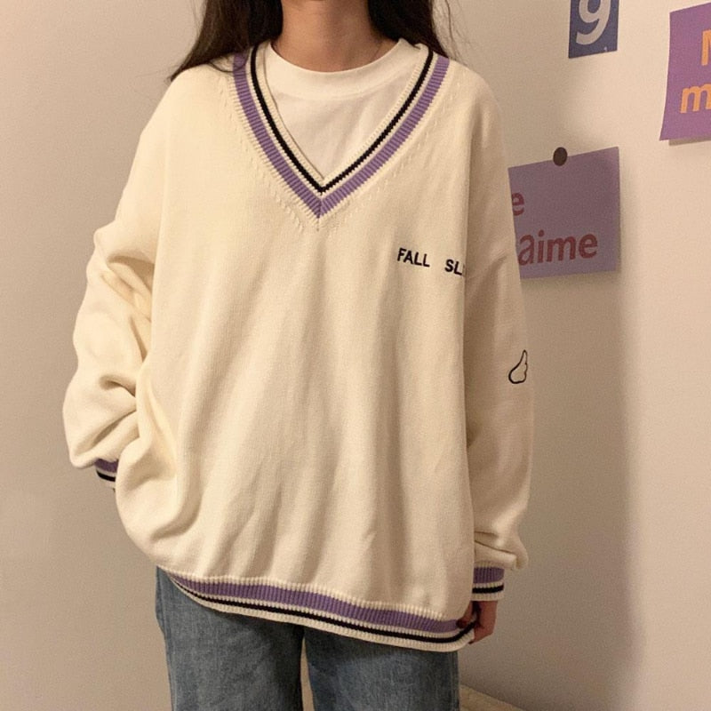 Frau in cremefarbenem V-Ausschnitt-Pullover mit lila Streifen, lässiger Stil, Herbstmode.