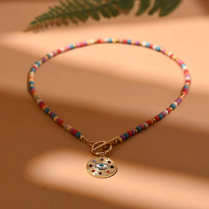 Bunte Perlenkette mit goldfarbenem Anhänger, Damenmode, Schmuckaccessoire, Boho-Stil.