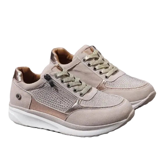 Ett par beige sneakers med blixtlås, glittrande strass och snören, fotograferade snett framifrån mot vit bakgrund 1