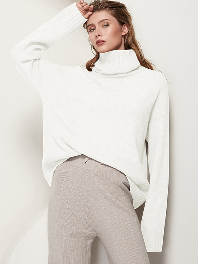 Frau in weißem Rollkragenpullover und beigen Strickhosen, modisch, elegant, Herbstmode.