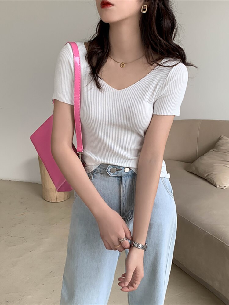 Frau in weißem Rippstrick-T-Shirt, blauer Jeans, rosa Tasche, modisch, lässig, modern.