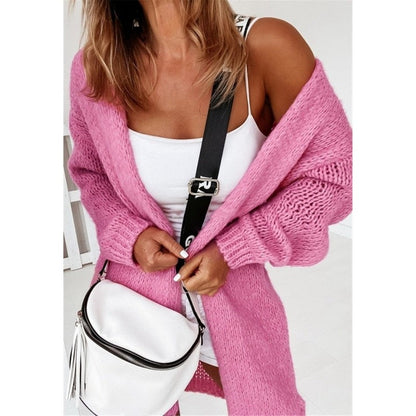 Frau in rosa Strickjacke mit weißem Top und weißer Umhängetasche, modisch, lässig.
