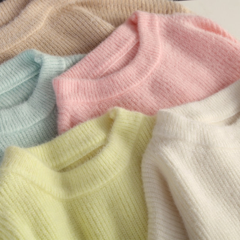 Fünf gestrickte Pullover in Pastellfarben: Beige, Blau, Rosa, Gelb, Weiß aus weicher Wolle.
