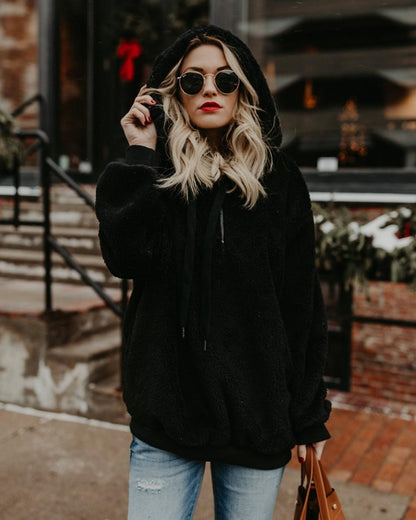 Frau in schwarzem Kapuzenpullover, Sonnenbrille, rote Lippen, lässiger Winterlook, Straße.