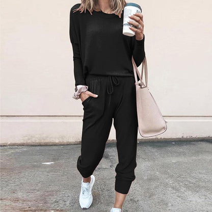 Frau in schwarzem Jogginganzug mit Kaffeebecher und beiger Tasche, lässige Mode.