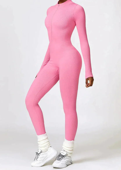 Frau in rosa, nahtlosem Jumpsuit, langärmelig, figurbetont, mit weißen Sneakers.