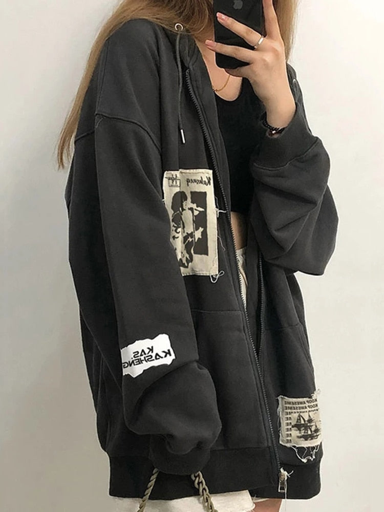 Frau in schwarzem Oversize-Hoodie mit Aufnähern, lässige Streetwear-Mode.
