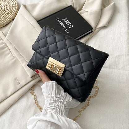 Schwarze gesteppte Handtasche mit goldener Schnalle auf beigem Blazer, elegantes Design.