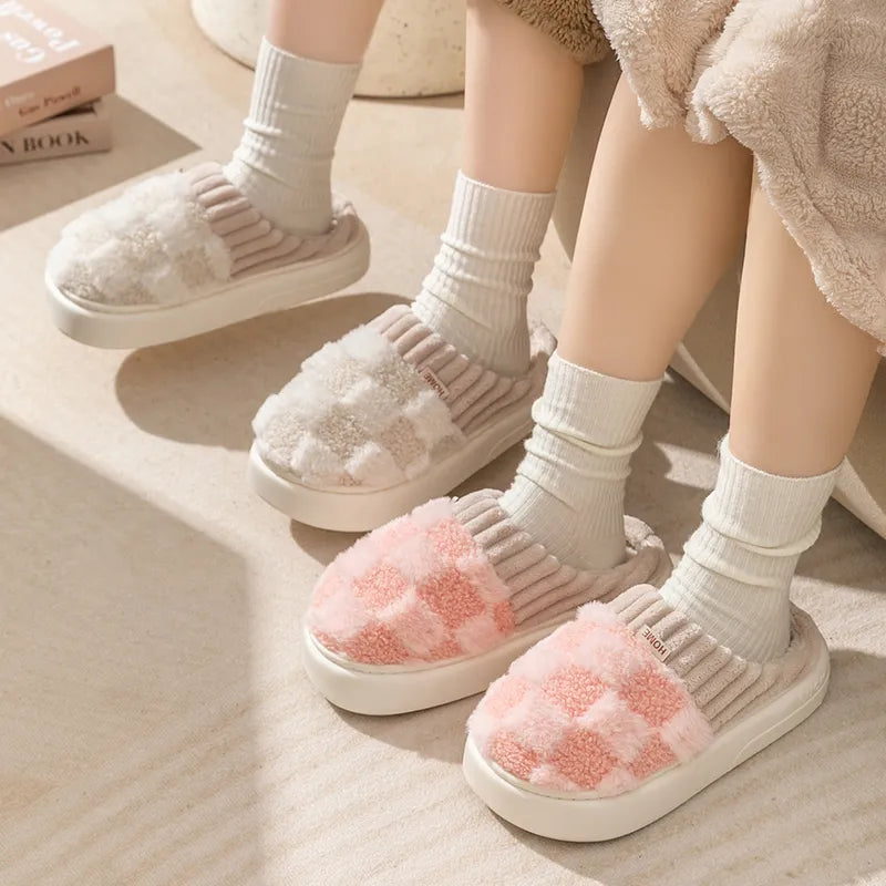 Zwei Paar flauschige Hausschuhe, kariert, rosa und beige, mit Socken auf Teppichboden.
