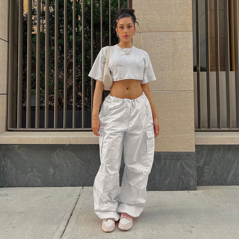 Frau in weißem Crop-Top und Cargo-Hose, urbaner Stil, Sommermode, Streetwear, Sneakers.