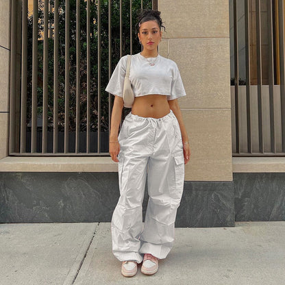 Frau in weißem Crop-Top und Cargo-Hose, urbaner Stil, Sommermode, Streetwear, Sneakers.