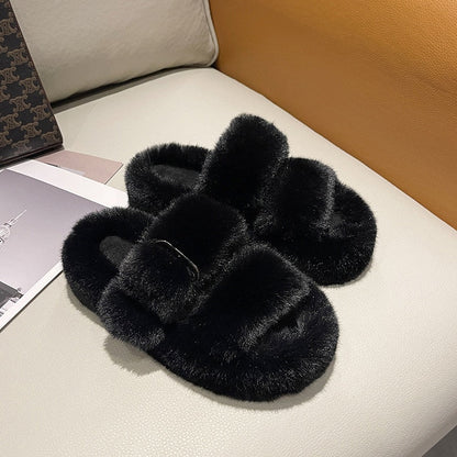 Schwarze flauschige Hausschuhe aus Kunstfell auf beigem Sofa, gemütliche Damenmode.