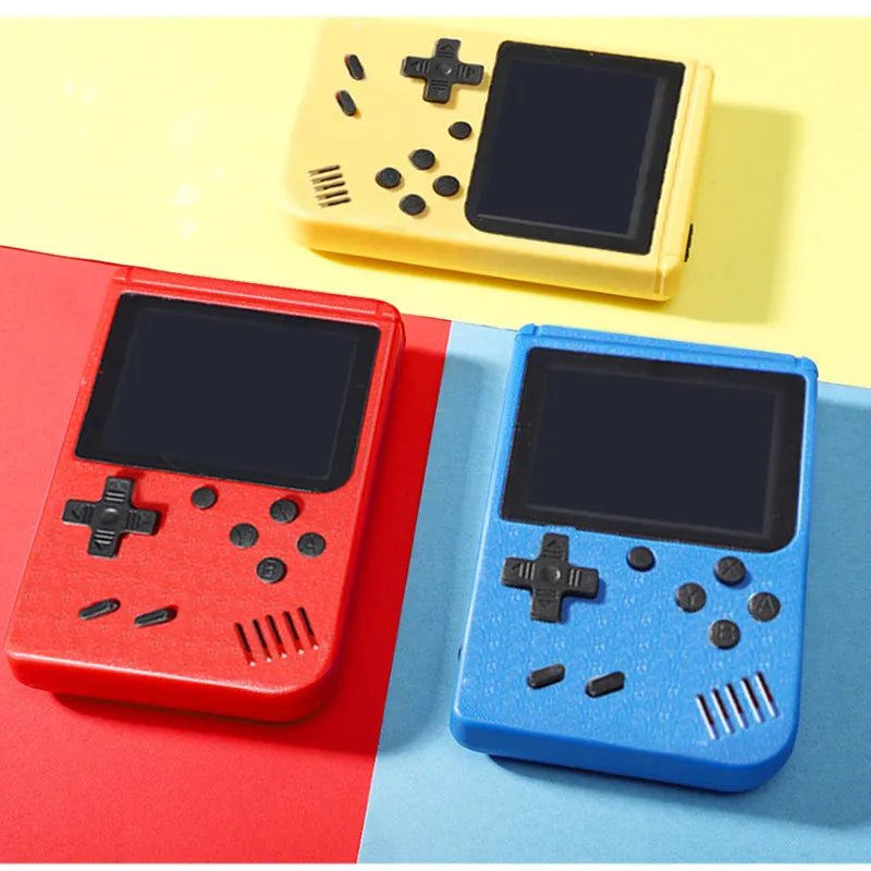 Drei tragbare Retro-Spielkonsolen in Rot, Gelb und Blau auf buntem Hintergrund.