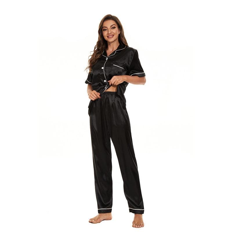Frau in schwarzem Satin-Pyjama-Set, kurzärmelig, mit Knöpfen, Nachtwäsche, bequem.