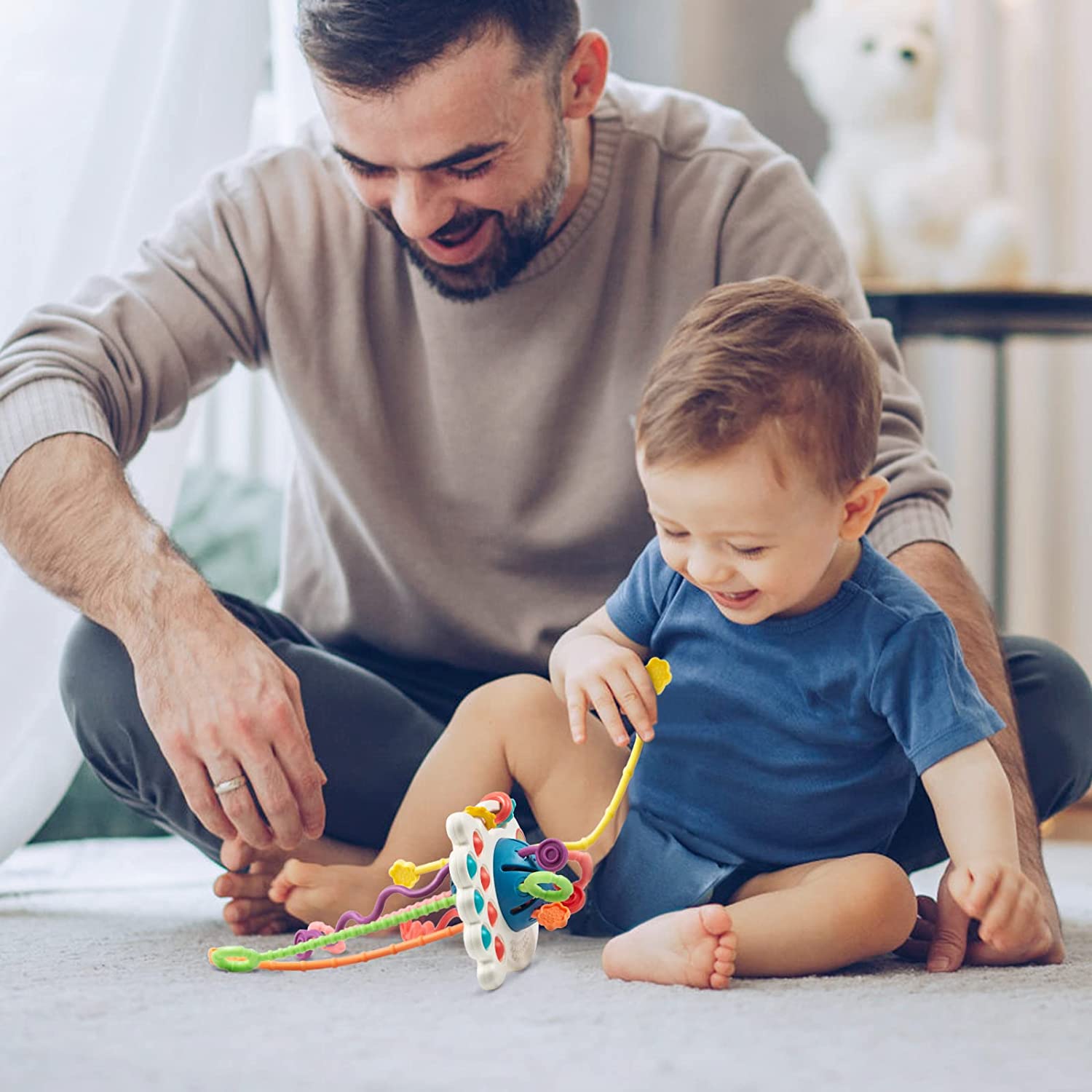 Vater und Kind spielen mit buntem Lernspielzeug auf Teppich im Wohnzimmer.