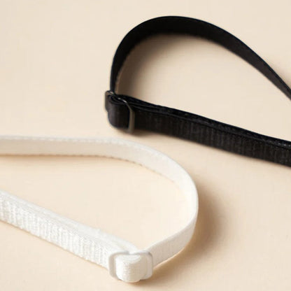 Schwarzes und weißes elastisches Stirnband-Set auf beigem Hintergrund, modisches Accessoire.