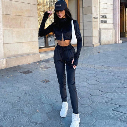 Frau in schwarzem Trainingsanzug und Celine-Cap, weiße Sneaker, städtische Kulisse.