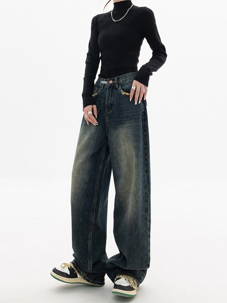Frau in schwarzem Pullover und weiten Jeans, modische Streetwear, lässiger Stil.