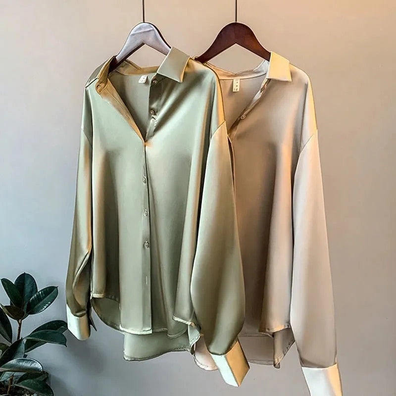 Zwei seidene Blusen in Grün und Beige auf Kleiderbügeln, elegante Damenmode, langärmlig.