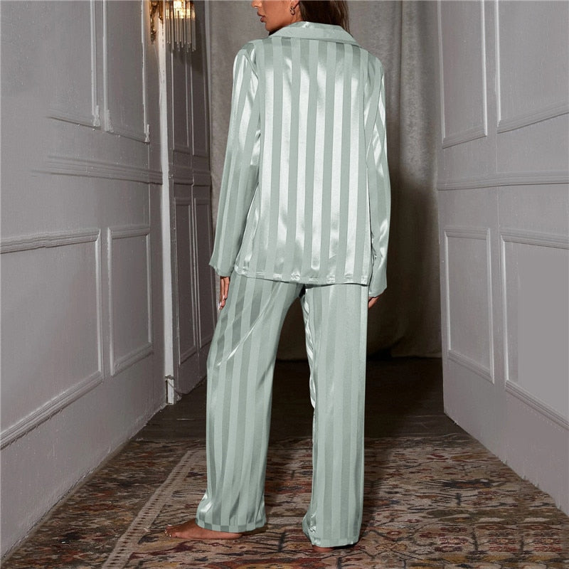 Frau in mintgrünem Satin-Pyjama mit Streifenmuster im Flur, Nachtwäsche, Damenmode.