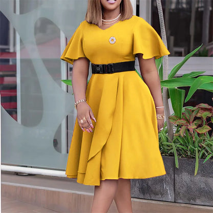 Frau im gelben Kleid mit Gürtel, elegantes Design, Sommermode, draußen, Pflanzen im Hintergrund.