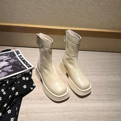 Beige Damenstiefel aus Leder mit Reißverschluss, modisch, elegant, auf Holztisch.