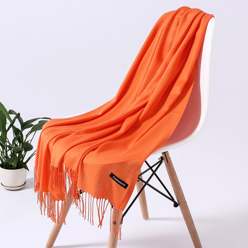Orangefarbener Kaschmirschal auf Stuhl, weiches Material, modisches Accessoire, Wohnzimmerdeko.
