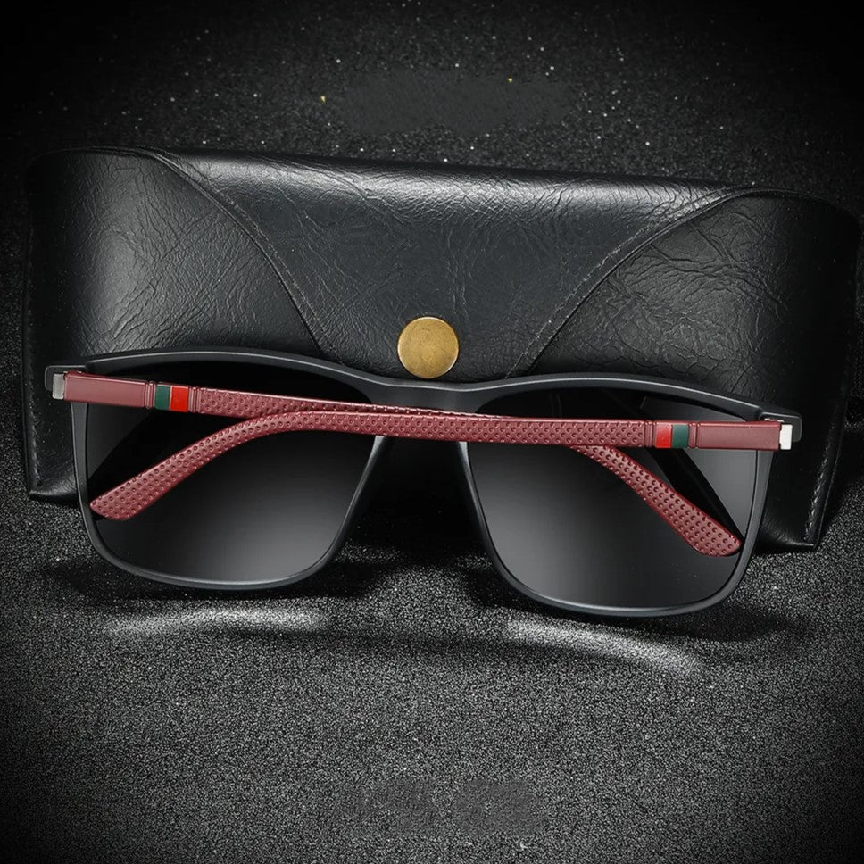 Schwarze Sonnenbrille mit roten Bügeln und Etui, modisches Accessoire, Unisex-Design.