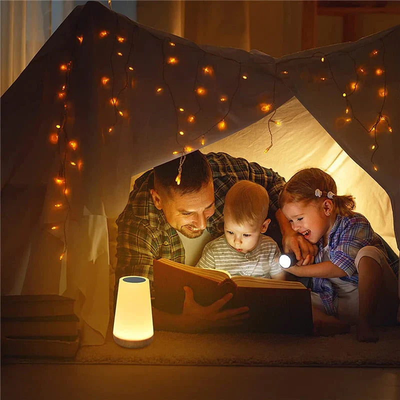 Vater liest Kindern im Zelt vor, umgeben von Lichterketten, gemütliche Familienzeit.