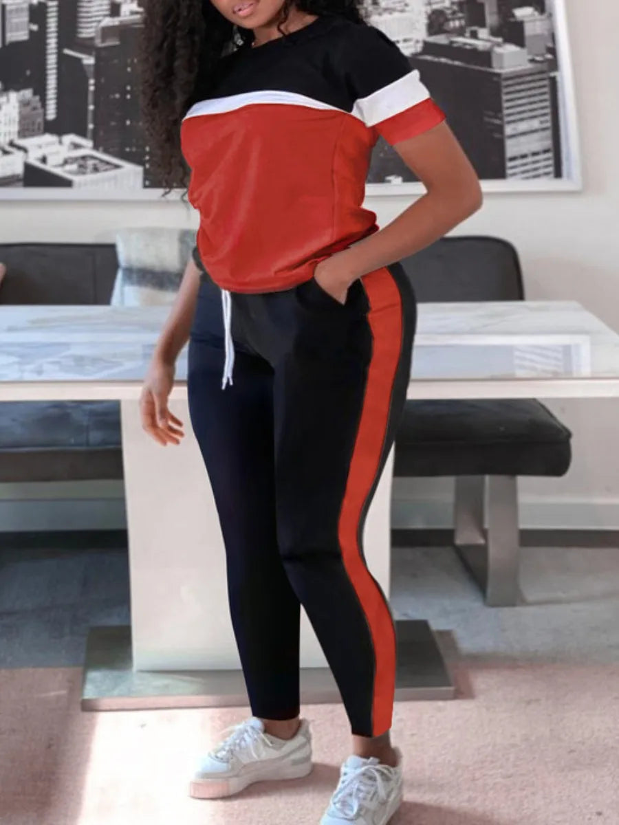 Frau in rotem und schwarzem Trainingsanzug, weißer Streifen, sportlich, modern, urbaner Hintergrund.